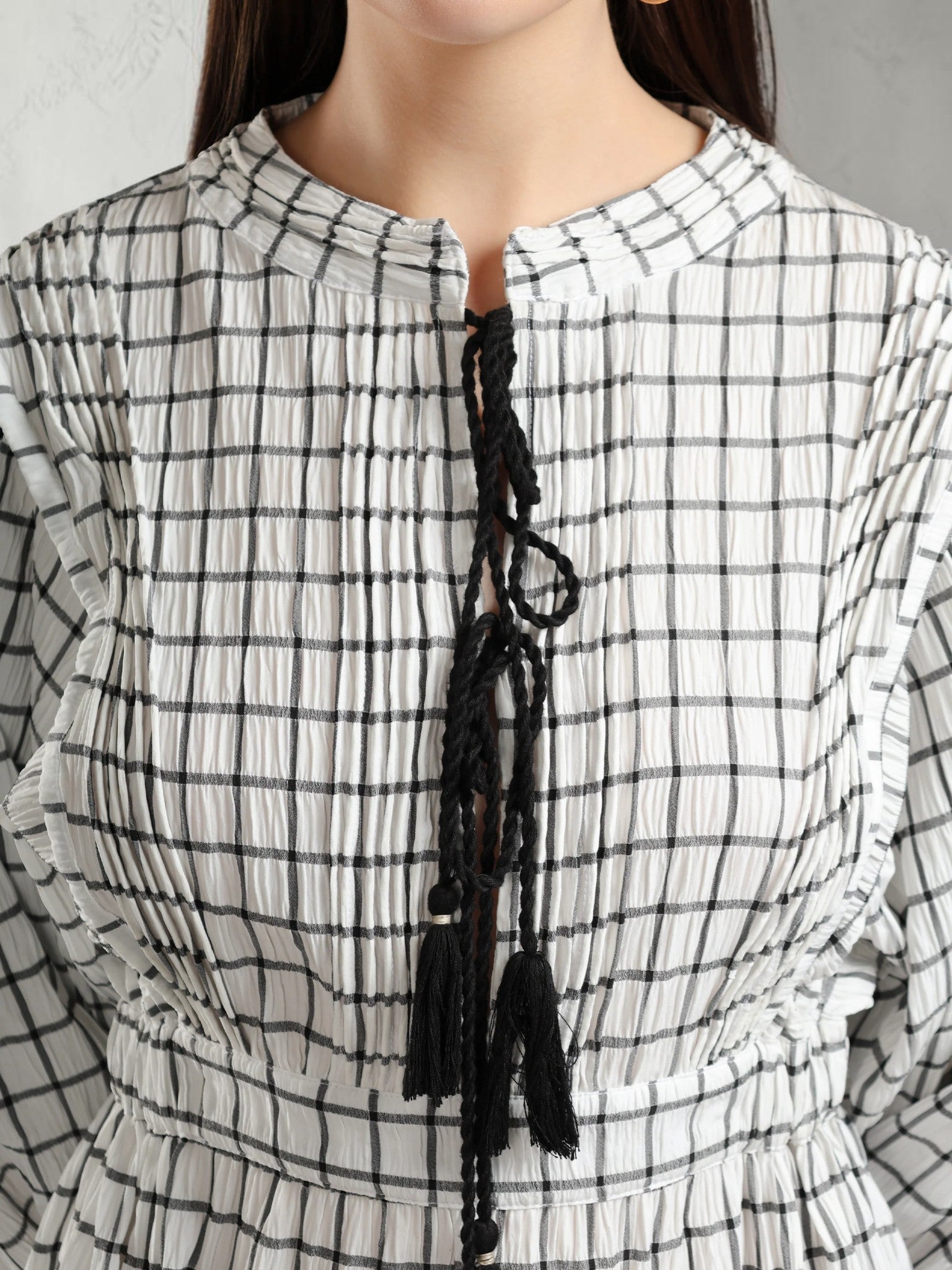 Close-up of a person wearing a black and white checkered dress with tassels.