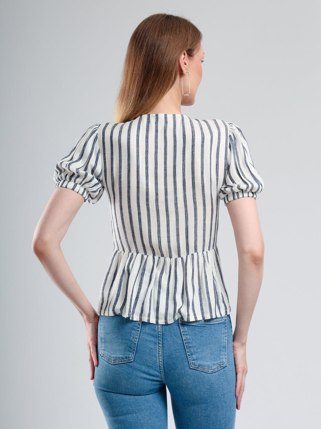 Woman wearing a striped blouse and blue jeans on a gray background