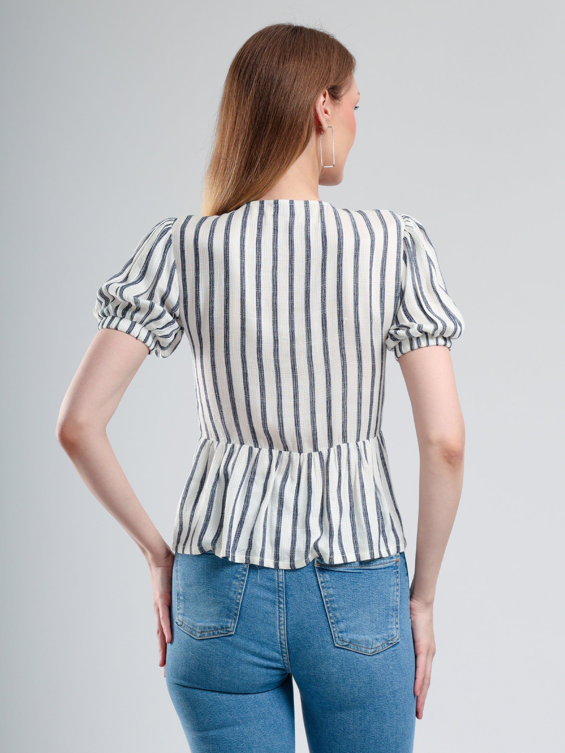 Woman wearing a striped blouse and blue jeans on a gray background