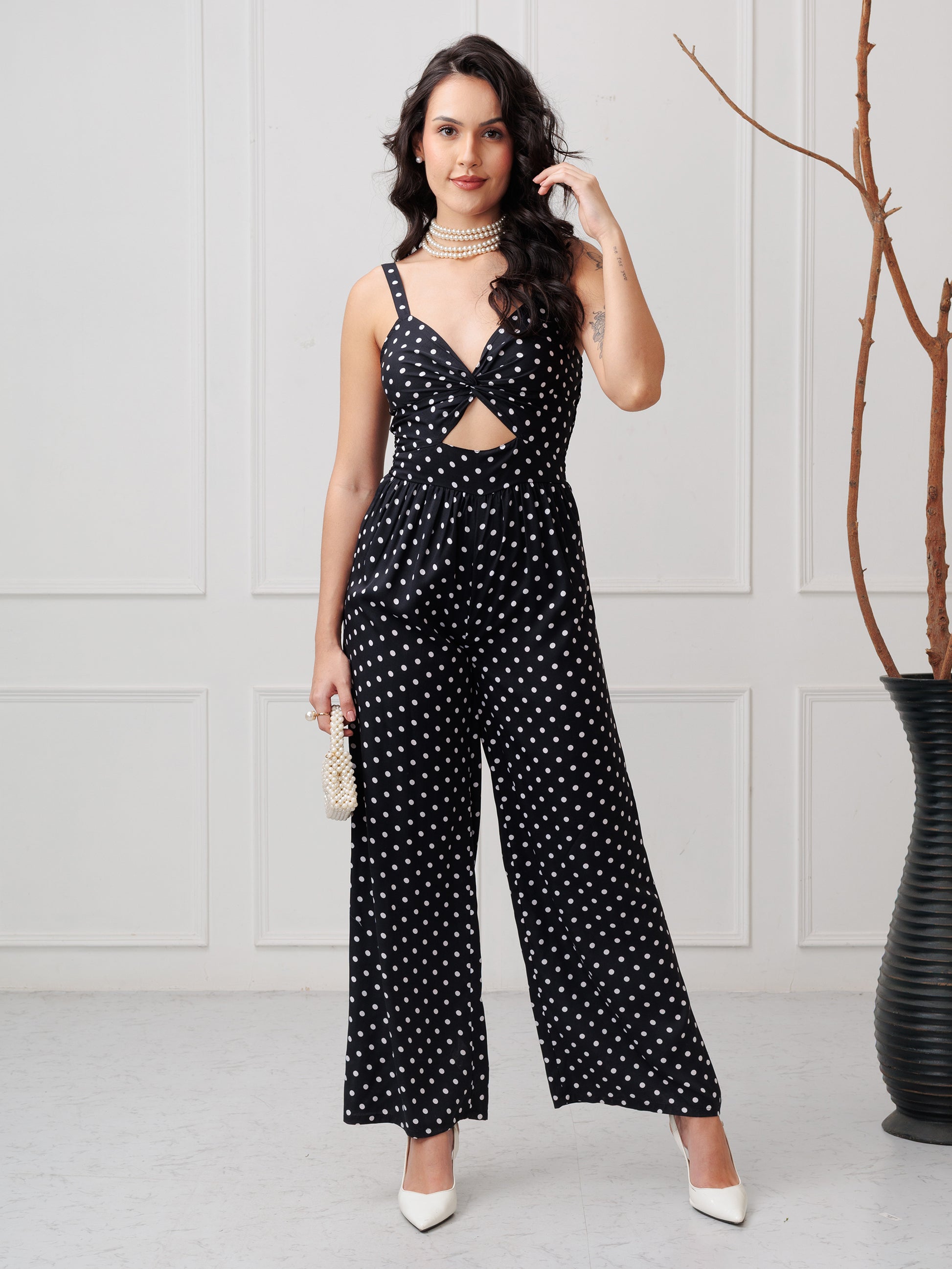 Woman wearing a black polka dot jumpsuit in a minimalistic setting