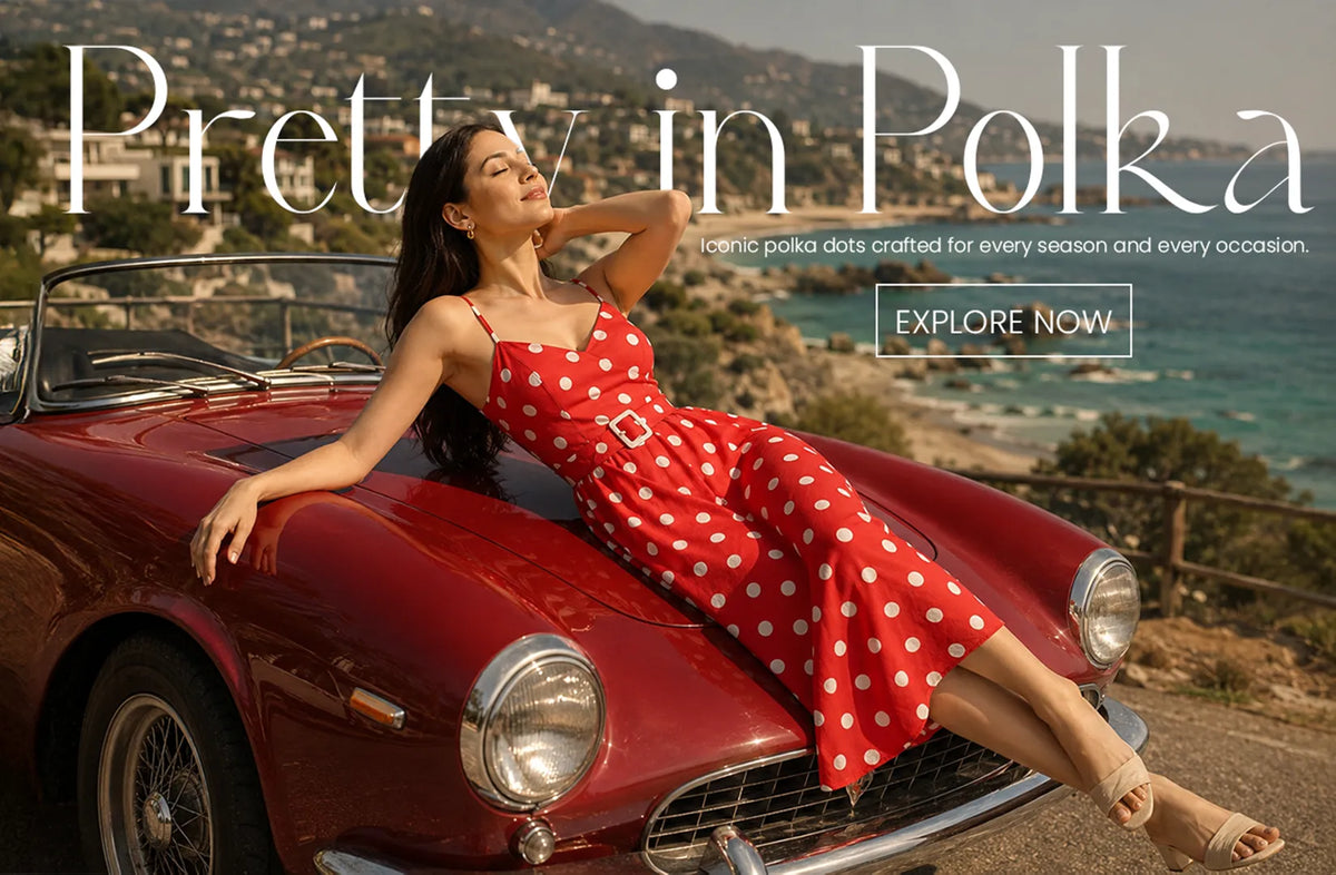 Red polka dot midi dress featured in a luxury fashion campaign with a vintage car and ocean-view backdrop, highlighting timeless women's summer style.